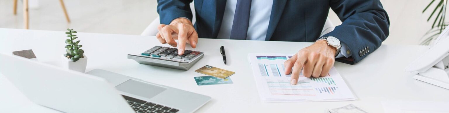 Un conseiller bancaire en costume calcule la capacité d'emprunt d'un client à l'aide d'une calculatrice et de documents financiers