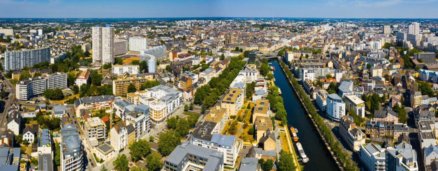 Vue aérienne d'une ville traversée par un canal, illustrant un marché immobilier attractif pour un investissement locatif.