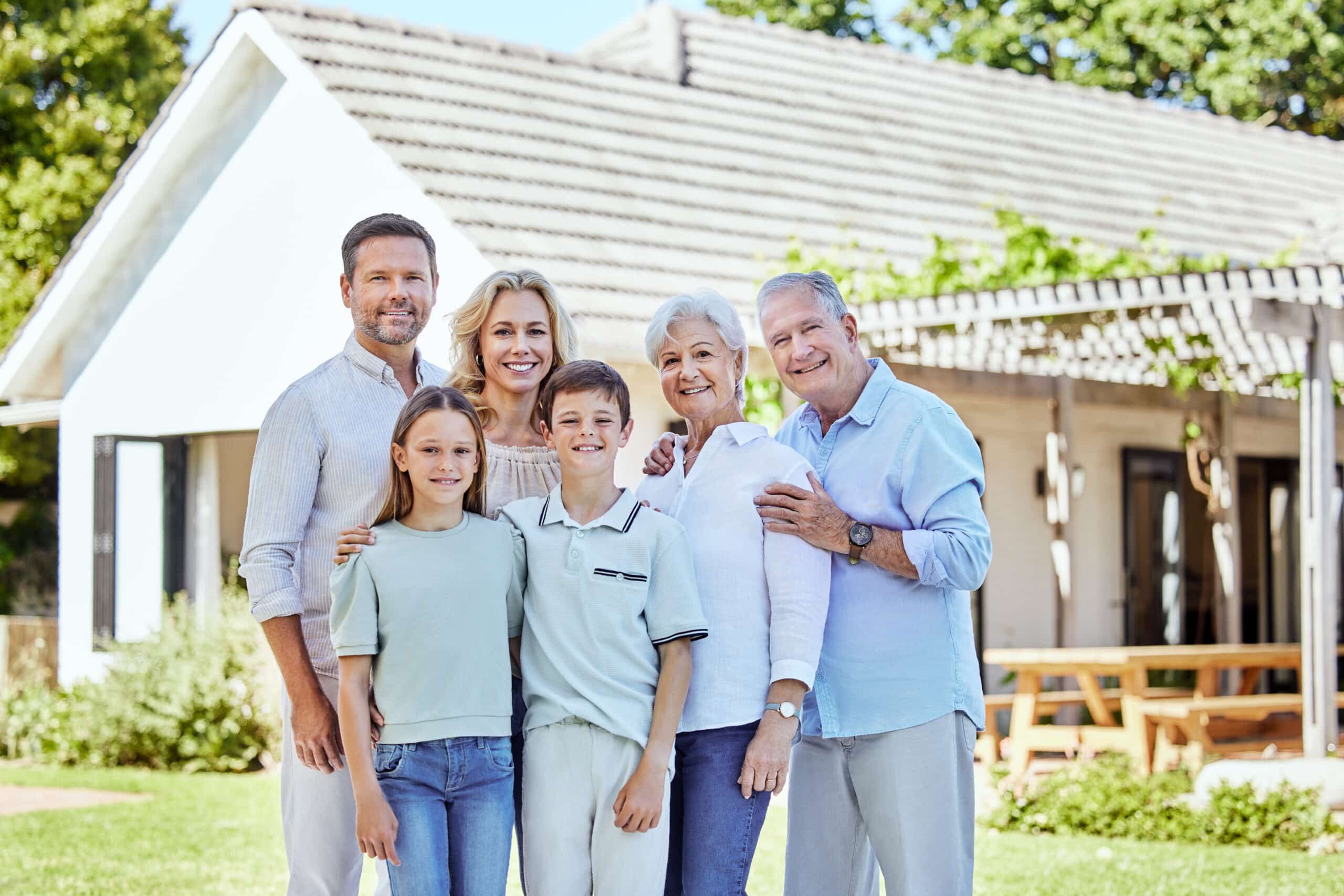Portrait d'une grande famille heureuse, en plein air près de la maison, réunie pour se soutenir, renforcer les liens ou partager l'amour. Sourires : la mère et le père avec leurs enfants, les grands-parents et plusieurs générations de personnes, ainsi que des frères et sœurs, dans le jardin derrière la maison.