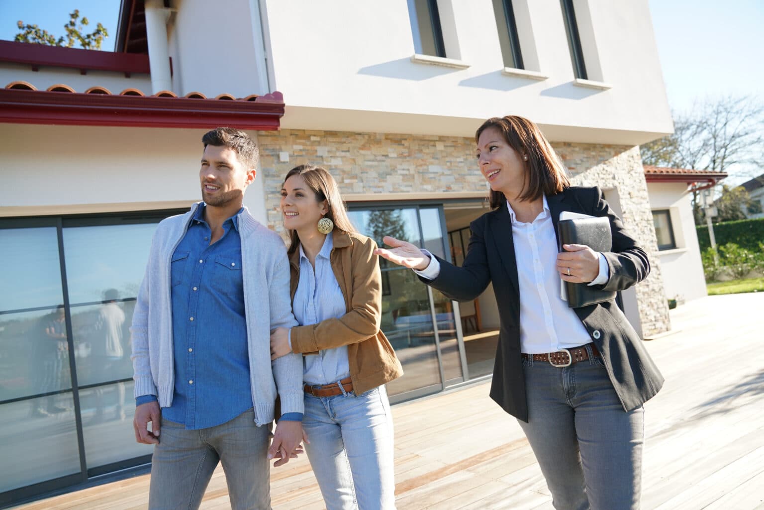 Un couple accompagné d'un agent immobilier visite une maison à vendre