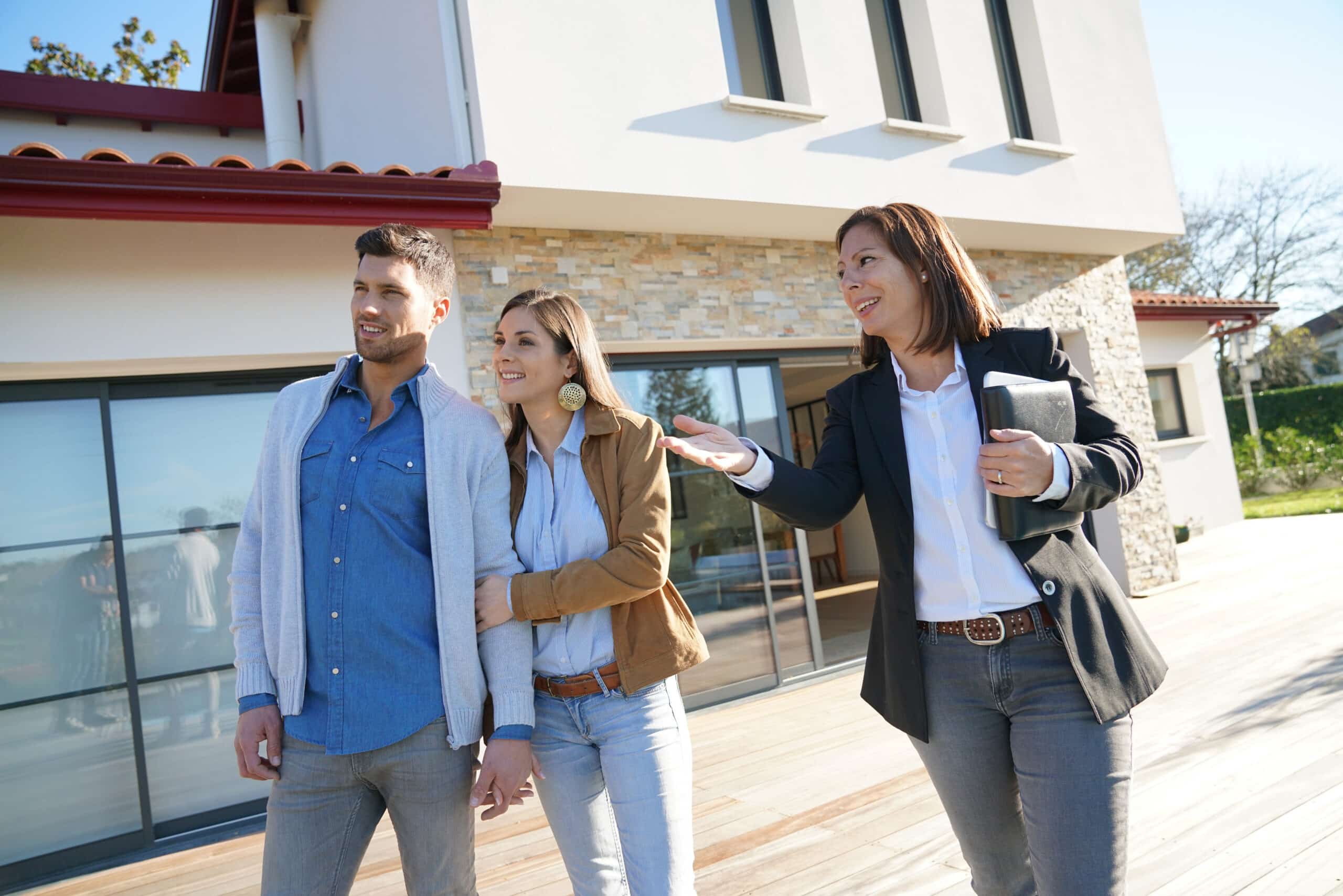 Un couple accompagné d'un agent immobilier visite une maison à vendre