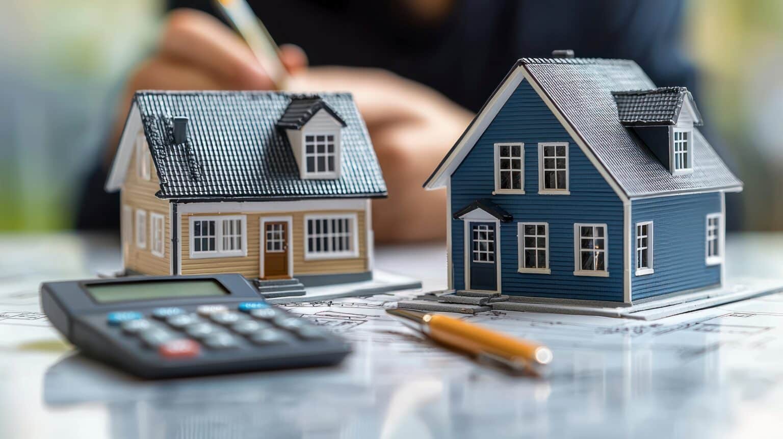 Des maisons miniatures, une calculatrice et une personne, l'accent étant mis sur l'accession à la propriété