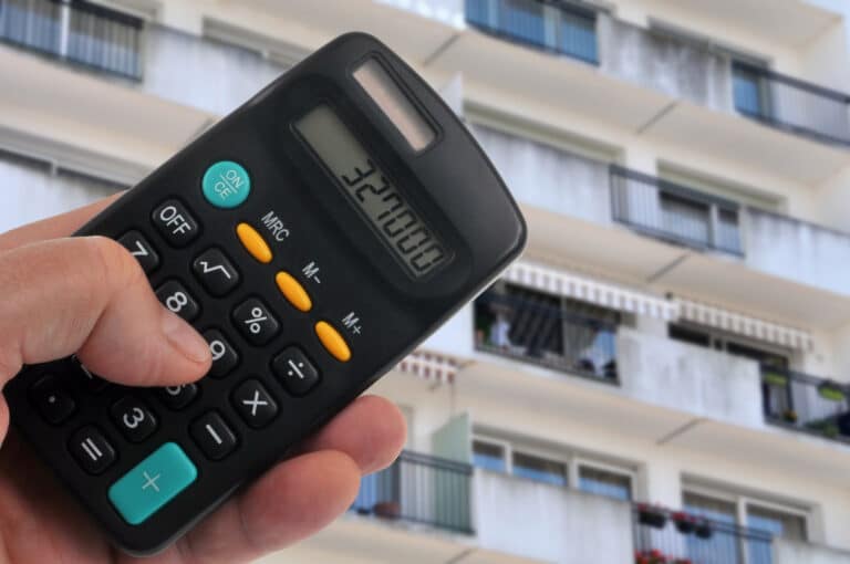 Concept d'estimation d'un appartement avec une calculatrice et une façade d'immeuble floue au second plan
