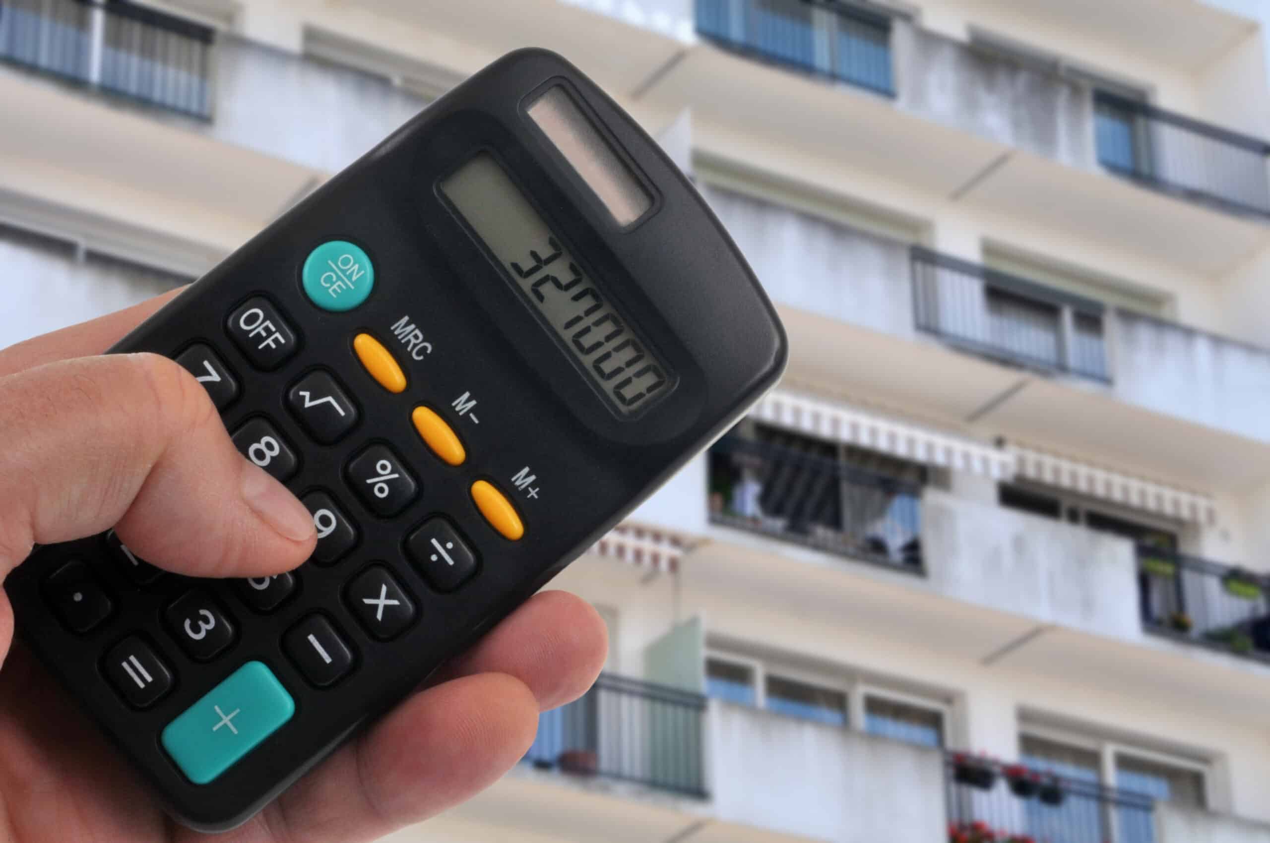 Concept d'estimation d'un appartement avec une calculatrice et une façade d'immeuble floue au second plan